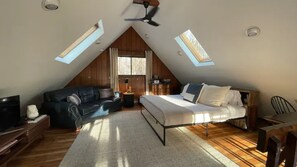 Une chambre confortable située sous les toits, avec un lit, un canapé et une télévision.