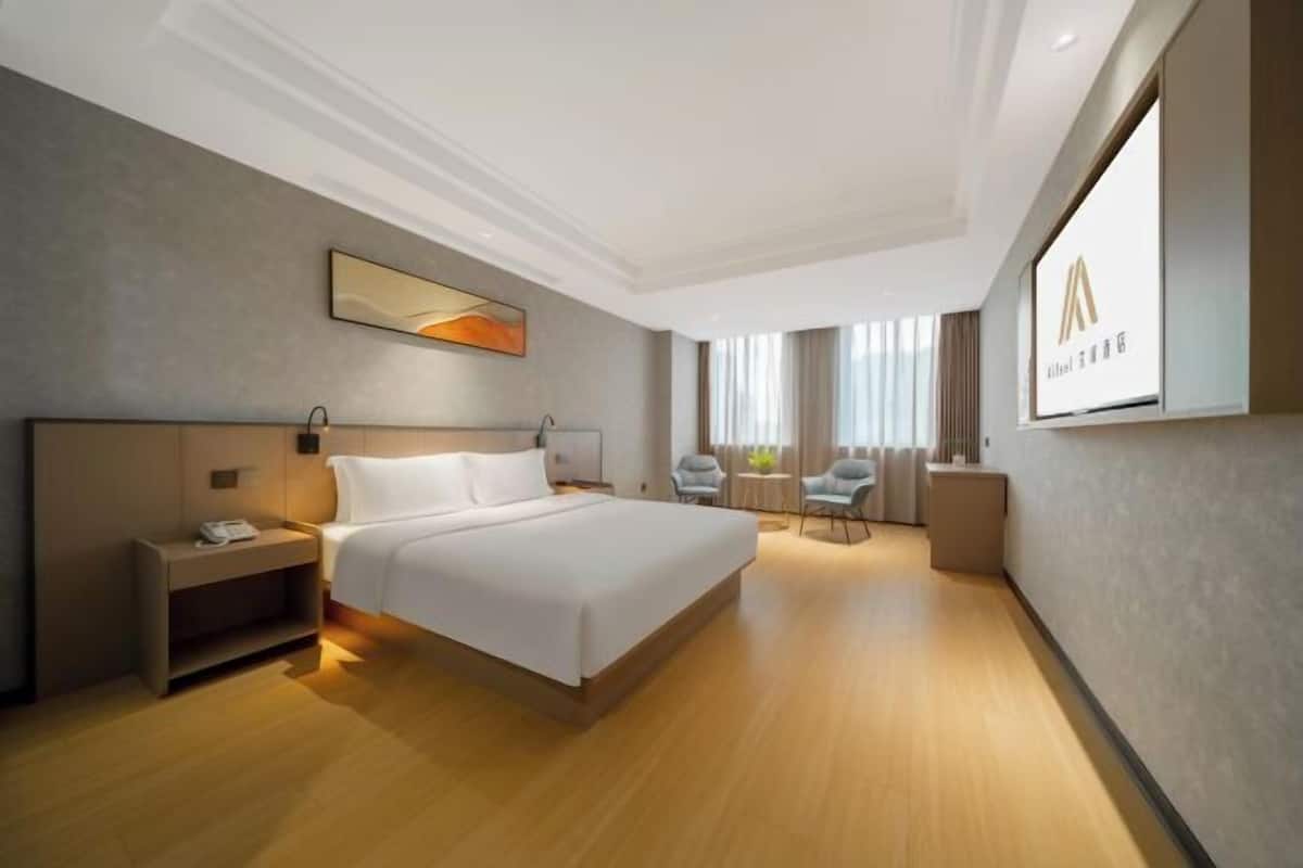 A hotel room with a large bed, bedside table, and a TV screen displaying a logo.