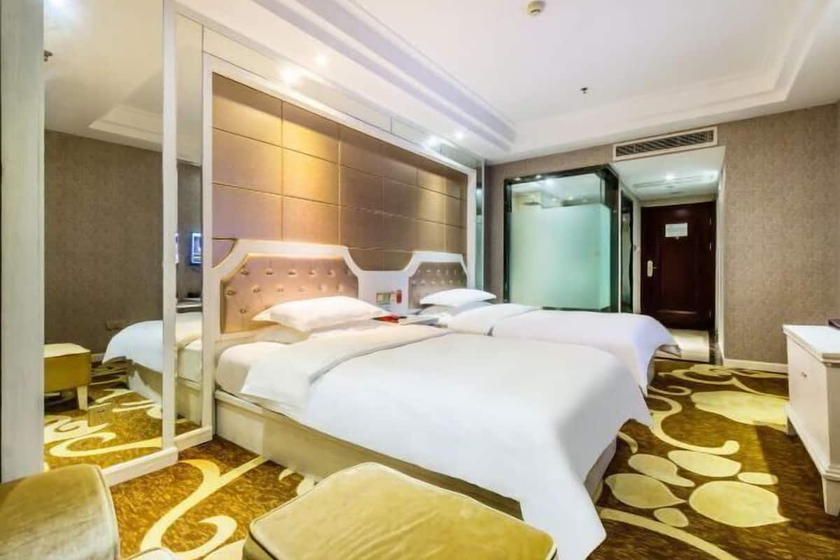 A hotel room with a large bed, a bedside table, a mirror, and a wardrobe.