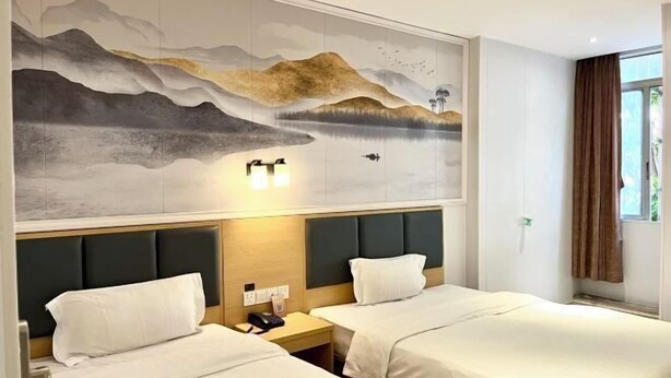Een hotelkamer met twee bedden, een groot wanddecor en een raam met gordijnen.