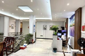 Un hall d’hôtel comprenant un comptoir d’accueil, un espace salon et un escalier.