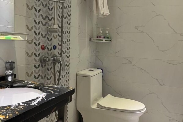 Une salle de bain avec un lavabo en marbre, des toilettes et une douche.