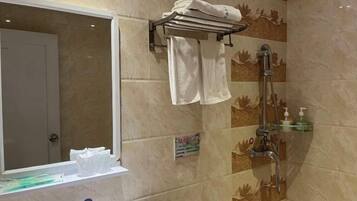 A bathroom with a shower, a towel rack, a mirror, and a shelf with toiletries.