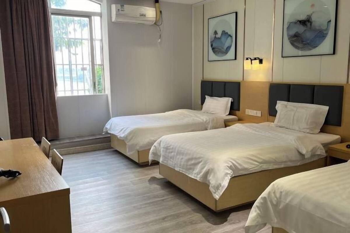 Et hotelværelse med to senge, et træskrivebord og billedkunst på væggene.