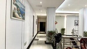 Een hotelgangen met een marmeren vloer, een trap en een eetgedeelte met stoelen en een tafel.