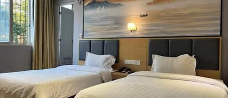 A hotel room with two beds, a large wall mural, and a window with curtains.