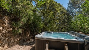 A hot tub in a natural setting with a wooden deck and surrounding greenery. - Charming apartments in Porto-Vecchio and Araggio, between the sea and the mounta (PORTO VECCHIO)