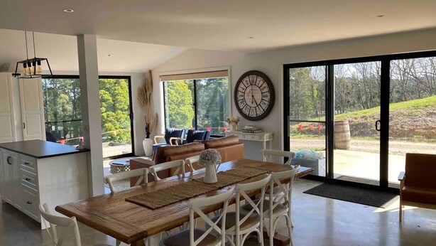 A spacious kitchen with a dining area, large windows, and a view of the outdoors.