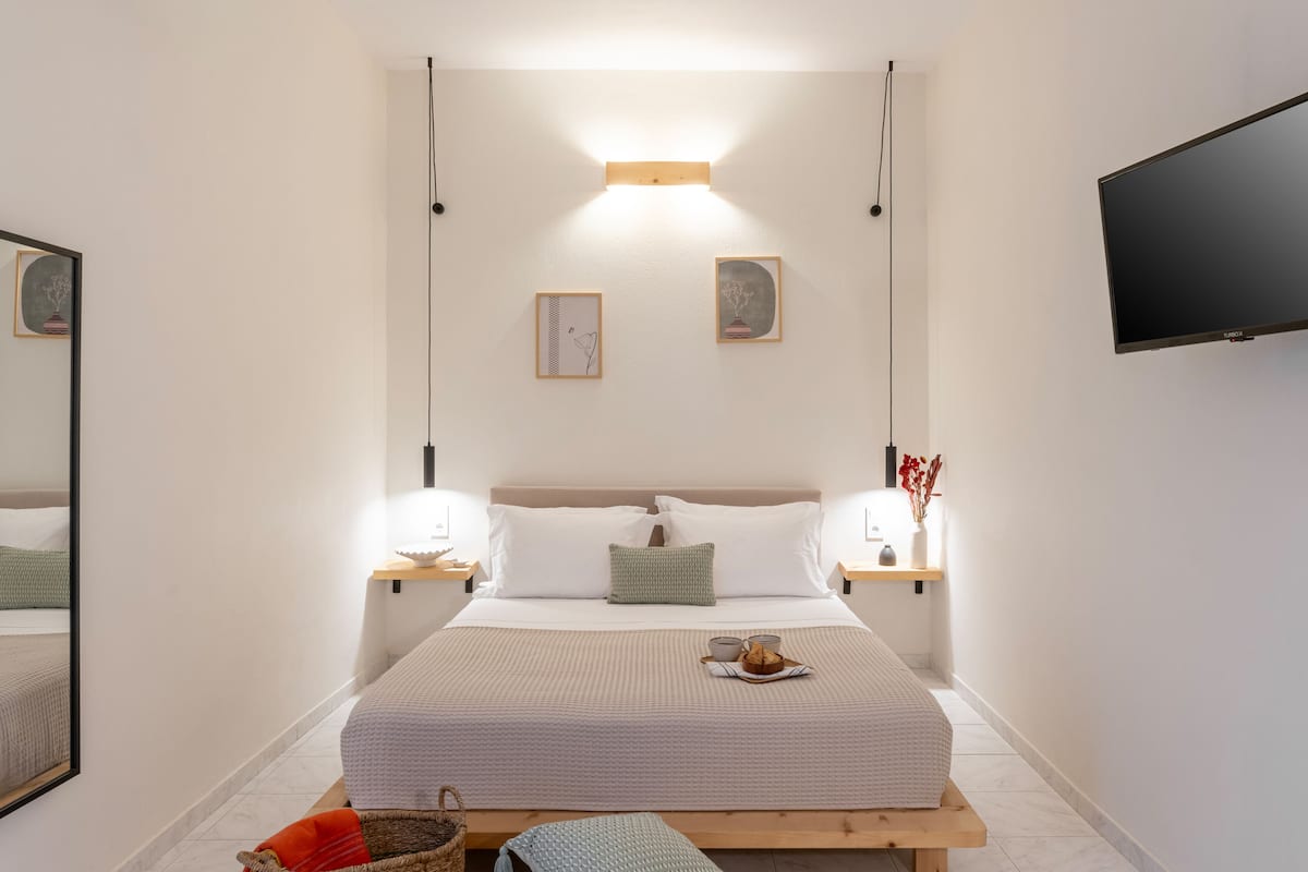 A modern bedroom with a large bed, bedside tables, a TV, and artwork on the walls.