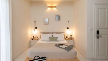 A bedroom with a bed, bedside tables, a hanging light fixture, a door, and a window with curtains.