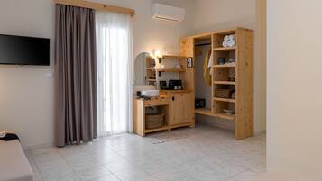 Una habitación de hotel moderna con un televisor de pantalla plana, un armario de madera, un lavamanos empotrado y un ventanal con cortinas.
