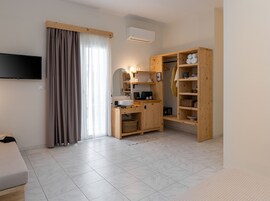 Una habitación de hotel moderna con un televisor de pantalla plana, un armario de madera, un lavamanos empotrado y un ventanal con cortinas.