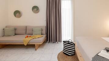 Un dormitorio moderno y minimalista con una cama plataforma de madera, un sofá con cojines, un bolso a rayas y una alfombra tejida.