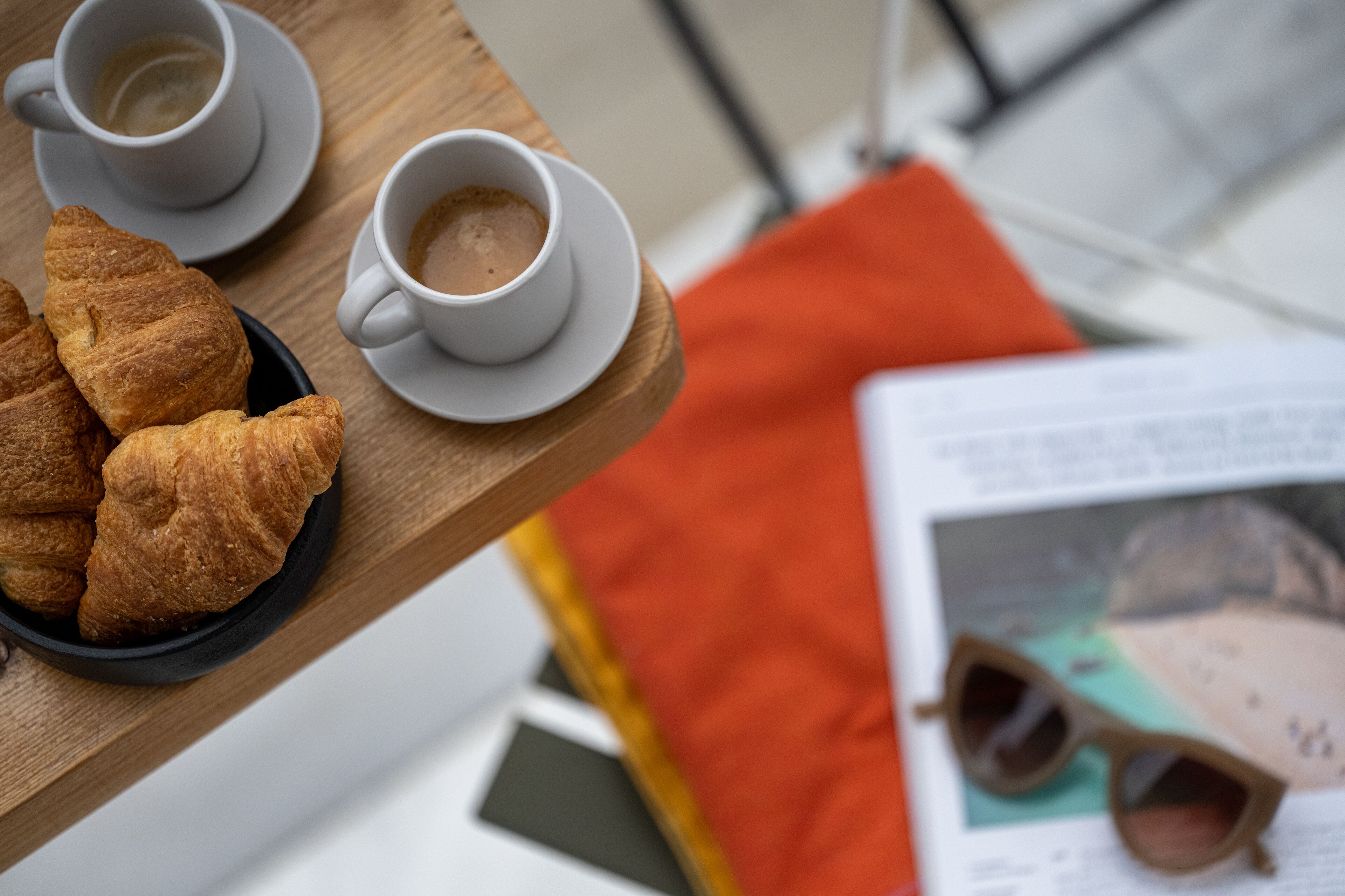 Uma bandeja com croissants e duas xícaras de café sobre uma mesa de madeira.