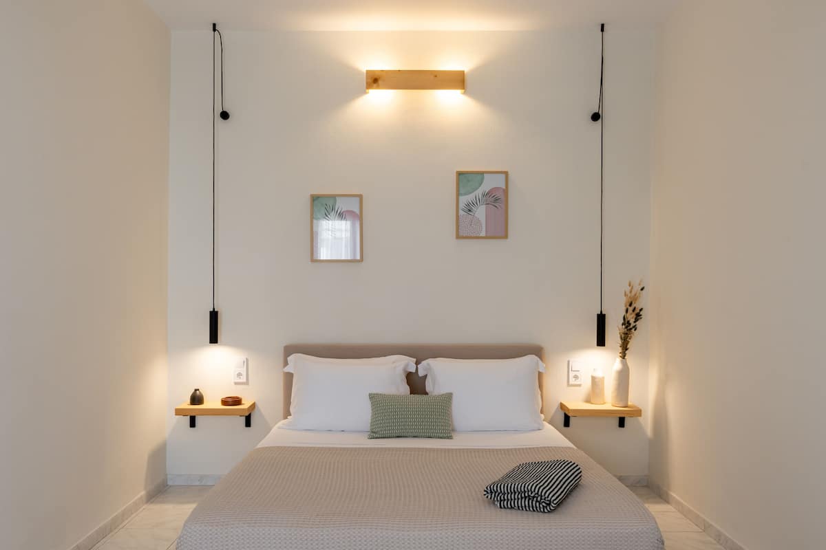 A neatly arranged bedroom with a wooden bed frame, two bedside tables, and wall-mounted lighting.