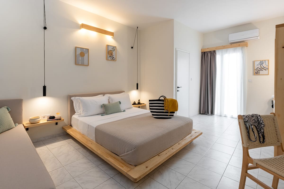 A modern bedroom with a large bed, bedside tables, a chair, and a view of the outside.