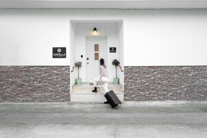 A person walking towards a white door with a sign reading "CAPELLA" on the wall.