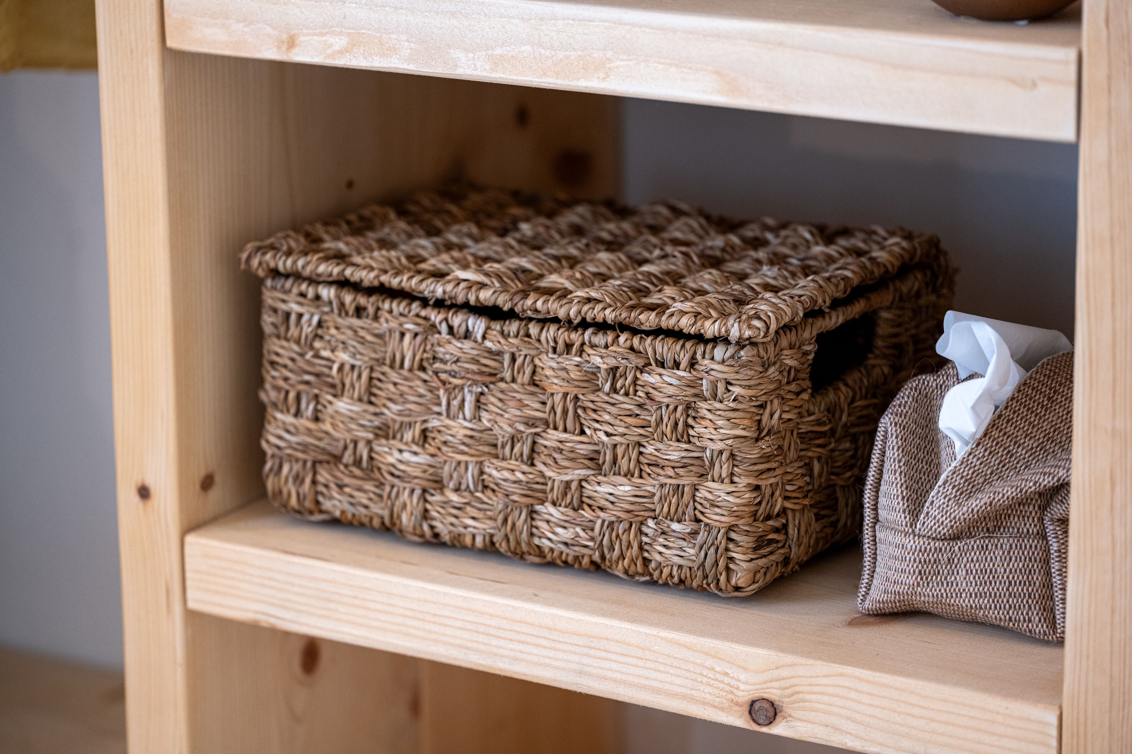 A wicker basket on a wooden shelf.
