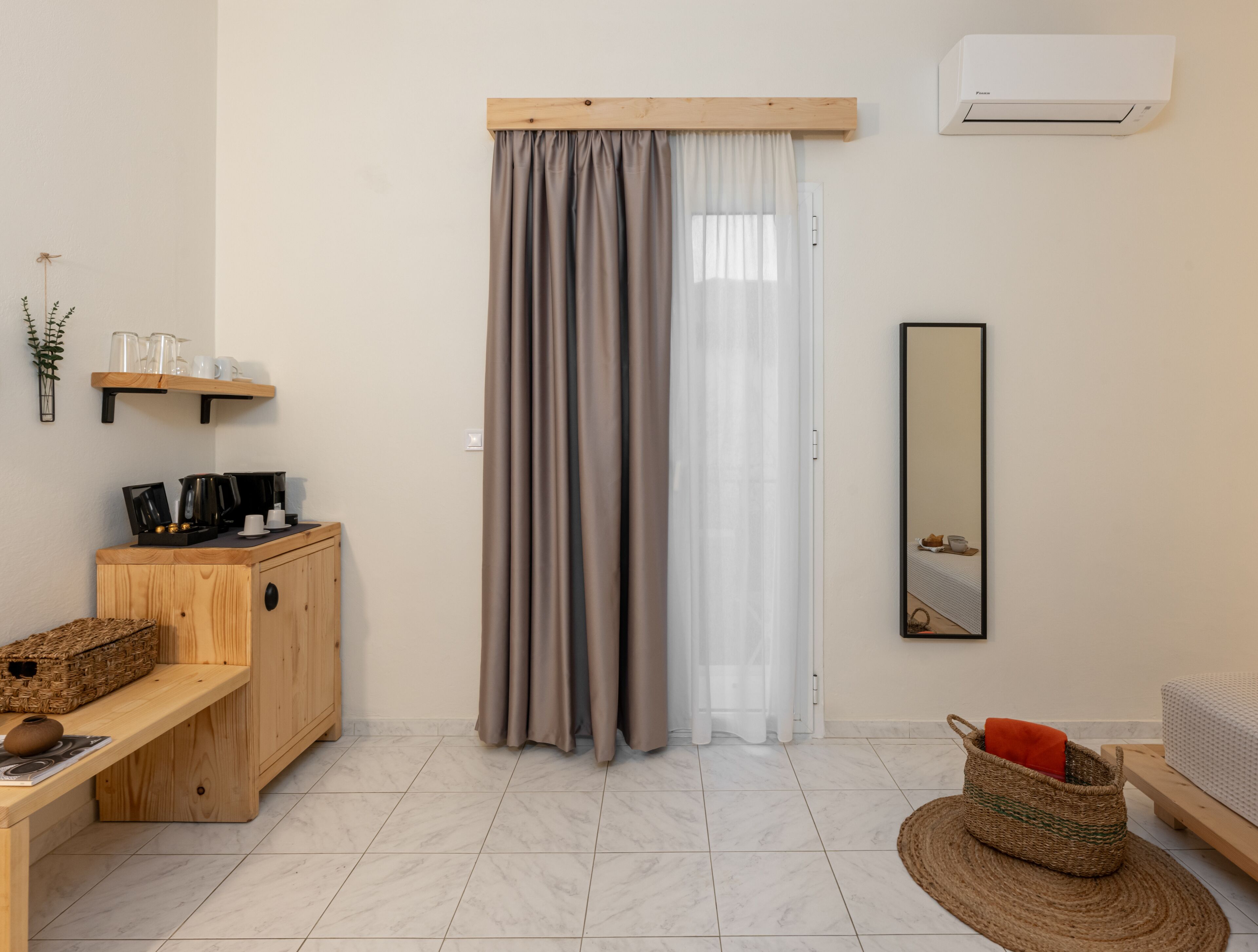 A room with a wooden cabinet, a mirror, a wicker basket, and a bed.