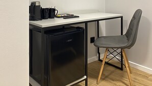Una kitchenette compacta con refrigerador integrado, una pequeña encimera y una silla.