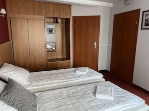 Quarto de hotel com duas camas, armários de madeira e um espelho.