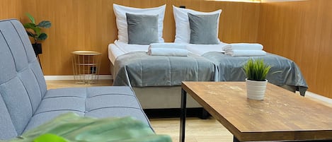 Un dormitorio moderno con una cama grande, un sofá, una mesita y una planta en maceta.