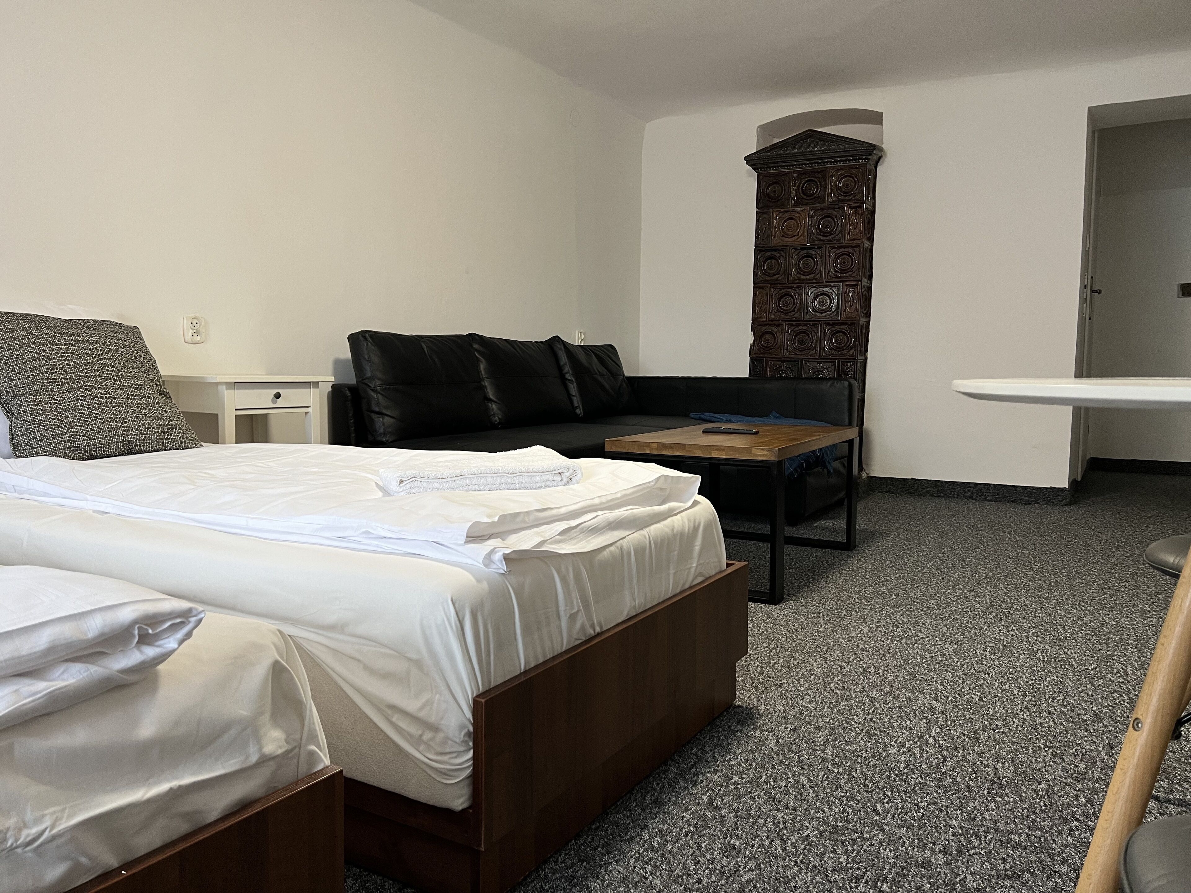 A hotel room with a large bed, a small sofa, a wooden table, and a decorative wall panel.