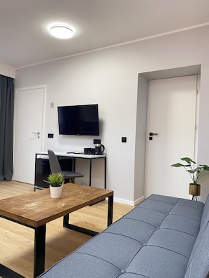 Uma sala de estar moderna com sofá, mesa de centro, TV e escrivaninha.