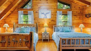 Una cabaña con dos camas de madera, una mesita de noche, una lámpara y un adorno de pared con motivos de ciervo.