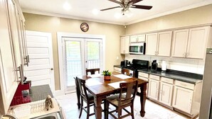 A kitchen with a dining table, chairs, a sink, cabinets, a ceiling fan, and a microwave. - Downtown Home Conveniently Located (Macon)