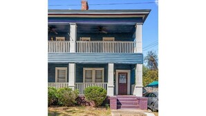 A two-story house with a front porch, a chimney, and a car parked in the driveway. - Downtown Home Conveniently Located (Macon)