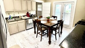 A kitchen with white cabinets, a dining table with chairs, a ceiling fan, and a clock on the wall. - Downtown Home Conveniently Located (Macon)
