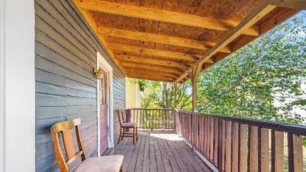 A wooden deck with a railing, two wooden chairs, and a table. - Downtown Home Conveniently Located (Macon)