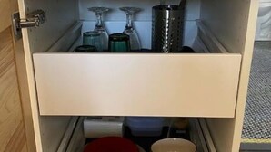 Een keuken met een magnetron op het aanrecht, een lade met keukengerei en een rode container.
