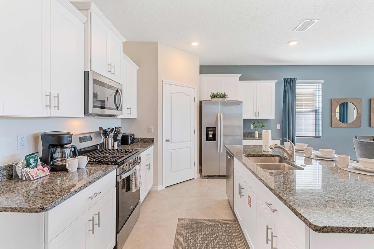 A modern kitchen with white cabinets, stainless steel appliances, and a granite countertop.
