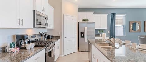 A modern kitchen with white cabinets, stainless steel appliances, and a granite countertop.