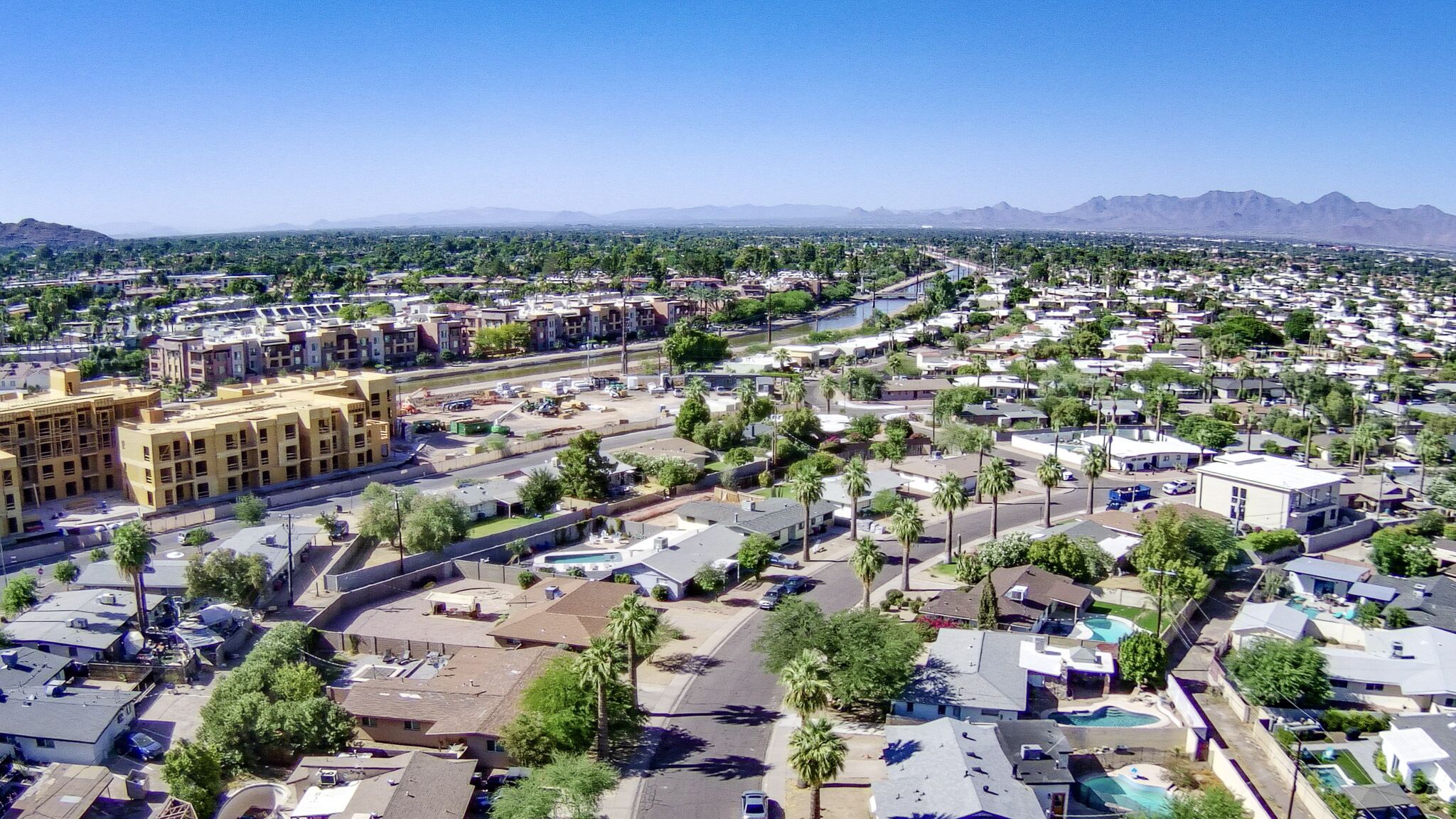 A residential area with multiple buildings, roads, and a large body of water in the distance.