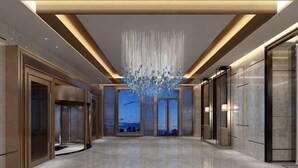 A spacious lobby with a modern chandelier, elevators, and a view through large glass doors. - Ya Le Xuan Hotel (Shehong)