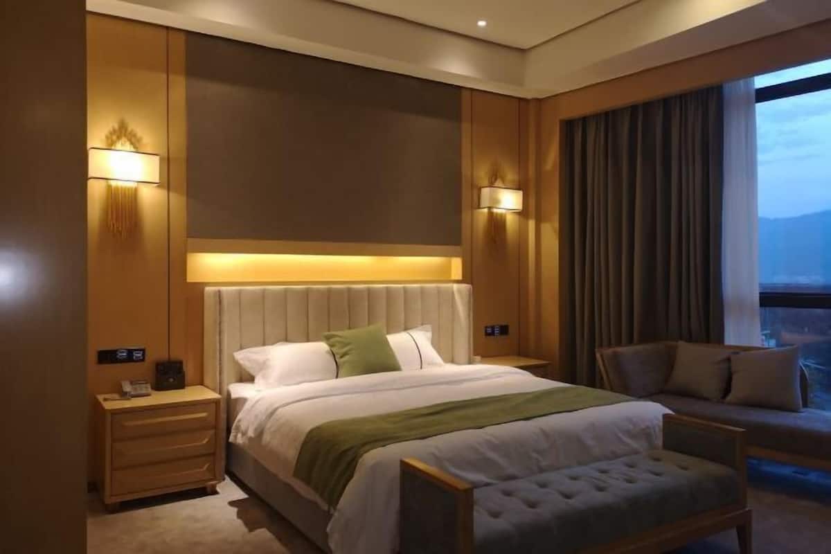 A hotel room with a bed, bedside tables, a chair, and a view of the outdoors.