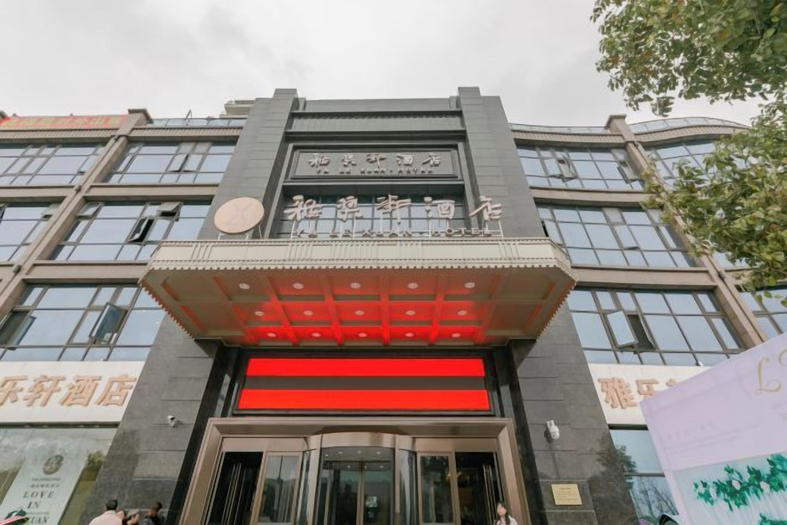 A hotel entrance with a modern facade, large glass windows, and a prominent entrance with a red accent.