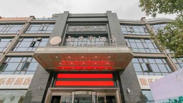 A hotel entrance with a modern facade, large glass windows, and a prominent entrance with a red accent.