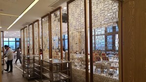 A corridor with decorative screens, metal shelves, and a view of a restaurant area. - Ya Le Xuan Hotel (Shehong)