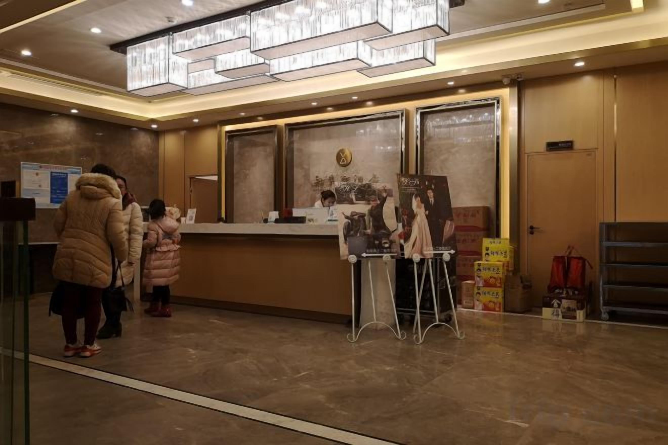 Zona de recepción de un hotel con mostrador, escritorio y una puerta a la derecha.