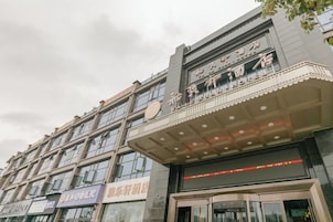 Un edificio de varios pisos con la entrada de un teatro, varias tiendas a nivel de calle y una fachada moderna.
