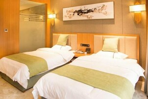 Habitación de hotel con dos camas, una obra de arte colgada en la pared y una mesita de noche con lámpara.