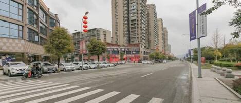 Uma rua ampla com faixa de pedestres, edifícios altos e carros estacionados.