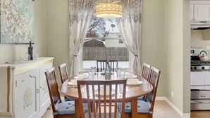 A dining room with a round table, six chairs, a chandelier, and a view through a window with curtains. - PROMO 10% WEEKLY AND 15% MONTHLY OFF
Naperville/Aurora, King Bed, Fenced Yard! (Aurora)
