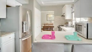 A modern kitchen with white cabinets, stainless steel appliances, and a dining area with a table and chairs. - PROMO 10% WEEKLY AND 15% MONTHLY OFF
Naperville/Aurora, King Bed, Fenced Yard! (Aurora)