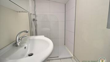Un bagno con un lavandino bianco, una doccia e pareti piastrellate.