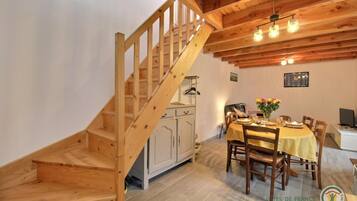 A wooden staircase leading to a dining area with a table set for four, a white cabinet, and a hanging light fixture above the table.